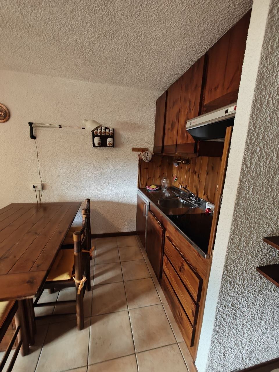 Lo stesso angolo cottura pulito e in ordine, con tavolo da pranzo e pavimento sgombro